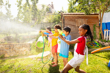 Kids shoot with water pistols on summer day