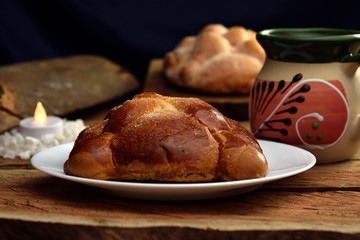 Bread of the dead, Mexican traditions days of the dead, traditional bread in the background sweet bread and a jar with coffee, all on wooden logs.