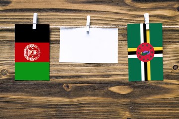 Hanging flags of Afghanistan and Dominica attached to rope with clothes pins with copy space on...