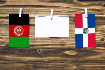 Hanging flags of Afghanistan and Dominican Republic attached to rope with clothes pins with copy...