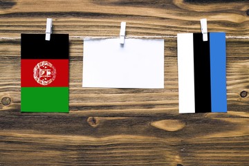 Hanging flags of Afghanistan and Estonia attached to rope with clothes pins with copy space on...