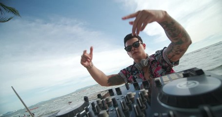 Happy asian male DJ playing music on a beach party.