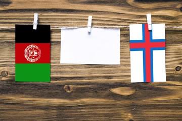 Hanging flags of Afghanistan and Faroe Islands attached to rope with clothes pins with copy space...