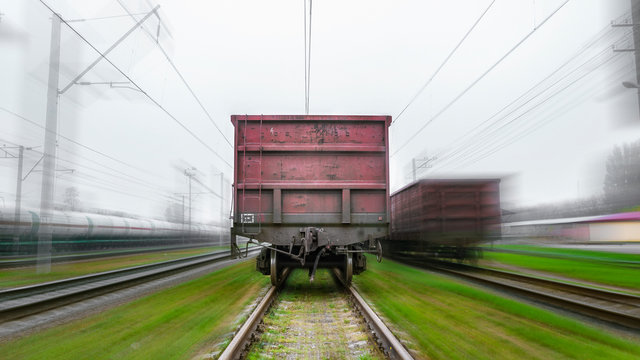 Freight train goes by rail. Back view. Blurred background gives a feeling of rapid movement. Fast delivery of heavy cargo by train
