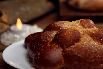 Pan de muerto, Mexican traditions days of the dead, traditional bread in the background sweet bread, an artificial candle, all on wooden logs.