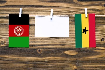 Hanging flags of Afghanistan and Ghana attached to rope with clothes pins with copy space on white...