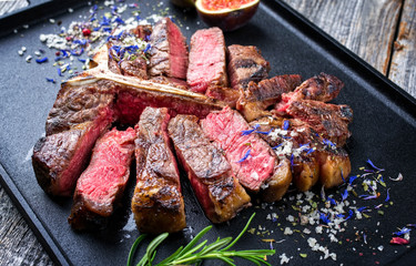 Traditional barbecue dry aged wagyu porterhouse steak sliced with fruit and spice as closeup on a modern design tray