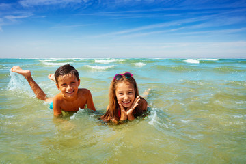 Boy and girl play in ocean waves on beach vacation