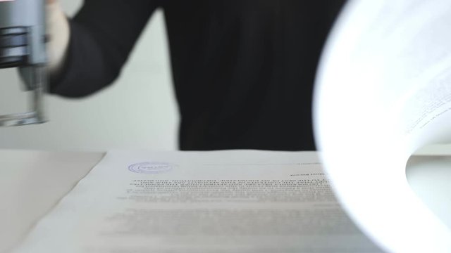 Female hand that puts an CERTIFIED stamp in the contract or documents.