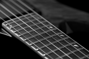 Fototapeta premium Fretboard of modern electric guitar on black background. 