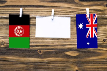 Hanging flags of Afghanistan and Heard Island and Mcdonald Islands attached to rope with clothes...