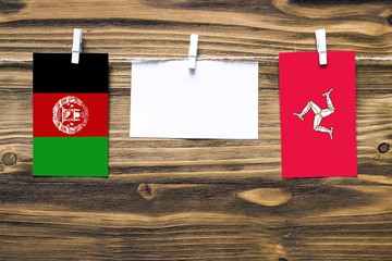 Hanging flags of Afghanistan and Isle Of Man attached to rope with clothes pins with copy space on...