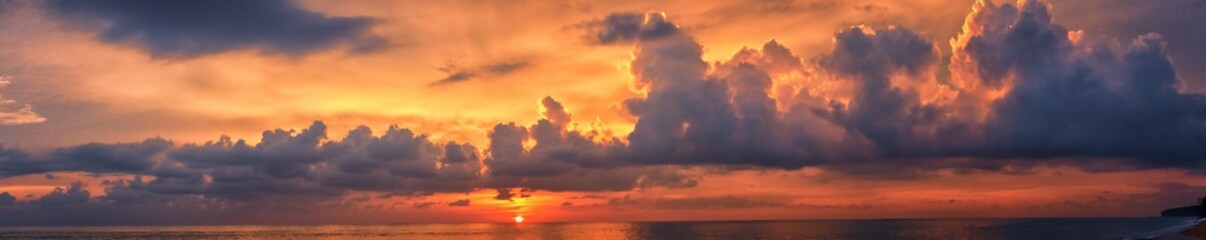 Phuket beach sunset, colorful cloudy twilight sky reflecting on the sand gazing at the Indian Ocean, Thailand, Asia.