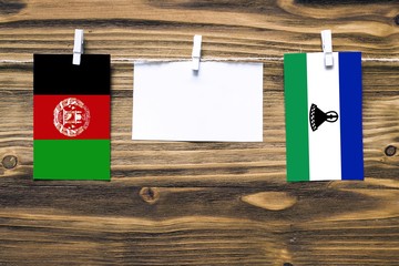 Hanging flags of Afghanistan and Lesotho attached to rope with clothes pins with copy space on...