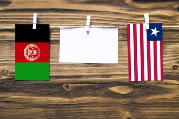 Hanging flags of Afghanistan and Liberia attached to rope with clothes pins with copy space on...