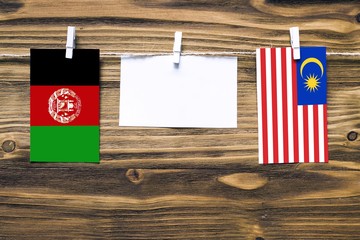 Hanging flags of Afghanistan and Malaysia attached to rope with clothes pins with copy space on...