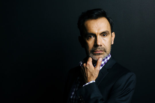 Portrait of a serious man in checkered shirt and jacket, isolated on black studio background