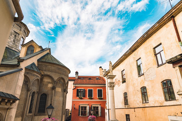 Fototapeta na wymiar medieval city back street square yard surrounded by old buildings and christian church architecture exteriors, European travel photography in clear day time 