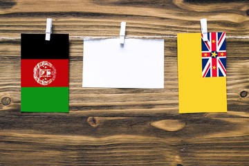 Hanging flags of Afghanistan and Niue attached to rope with clothes pins with copy space on white...