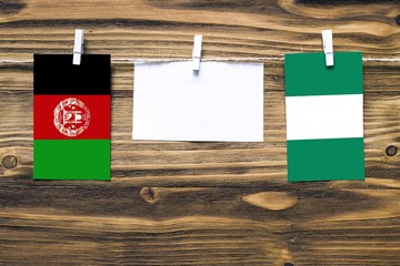 Hanging flags of Afghanistan and Nigeria attached to rope with clothes pins with copy space on...