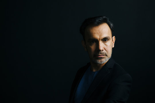 Portrait of a mature man looking at camera, isolated on black studio background