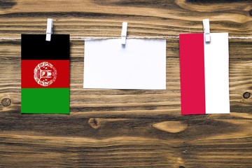 Hanging flags of Afghanistan and Poland attached to rope with clothes pins with copy space on white...