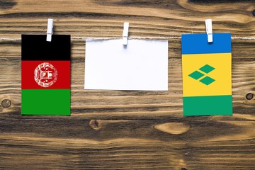 Hanging flags of Afghanistan and Saint Vincent And The Grenadines attached to rope with clothes...