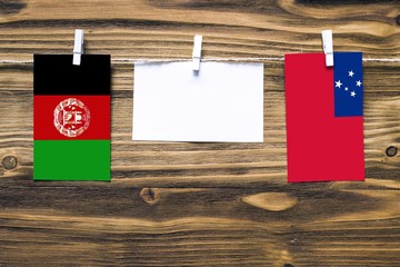 Hanging flags of Afghanistan and Samoa attached to rope with clothes pins with copy space on white...