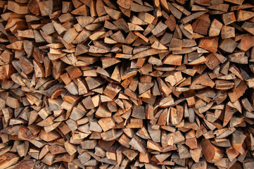 Firewood pile stacked chopped wood trunks for winter heating fireplace.