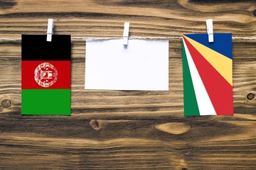 Hanging flags of Afghanistan and Seychelles attached to rope with clothes pins with copy space on...