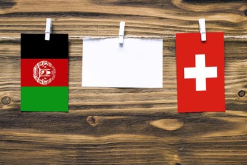 Hanging flags of Afghanistan and Switzerland attached to rope with clothes pins with copy space on...