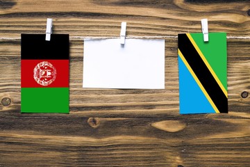Hanging flags of Afghanistan and Tanzania attached to rope with clothes pins with copy space on...