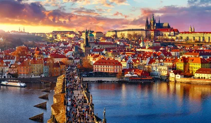 Papier Peint photo Marron profond Vue panoramique au-dessus du pont Charles Château de Prague et de la rivière Vltava Prague République tchèque. Paysage pittoresque avec des maisons de la vieille ville au coucher du soleil avec des toits tégulaires rouges et une tour de broche.