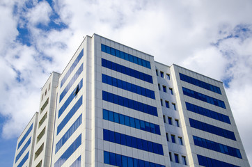 Architectural background, fragment of a modern office building against blue sky with clouds