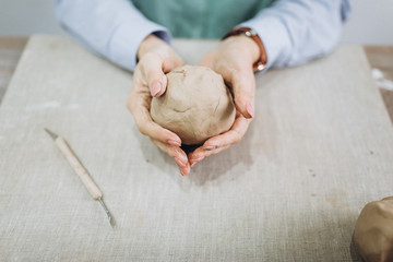 The potter's hands are shaped a cup from a clay. The process of creating pottery. The master ceramist works in his studio. Close-up, only hands. Crockery from clay own hands.