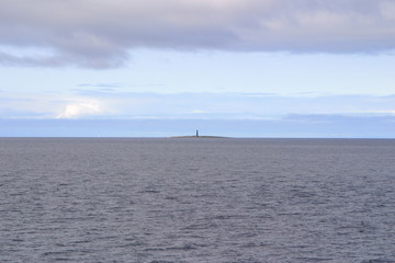 Calm White sea and lighthouse in the distance on the island
