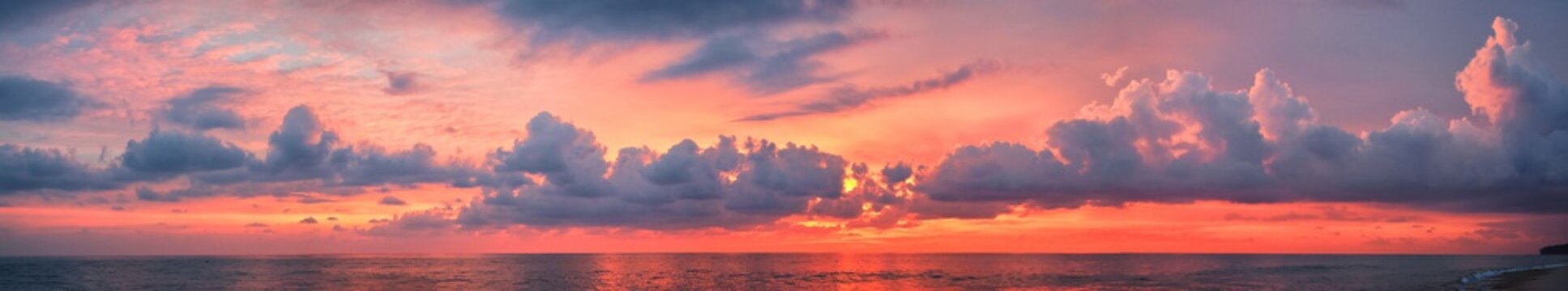 Phuket beach sunset, colorful cloudy twilight sky reflecting on the sand gazing at the Indian Ocean, Thailand, Asia.