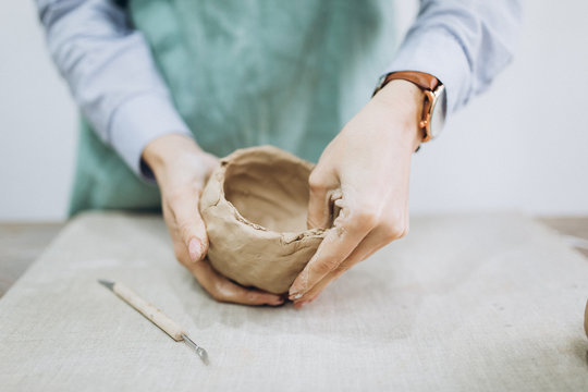 The potter's hands are shaped a cup from a clay. The process of creating pottery. The master ceramist works in his studio. Close-up, only hands. Crockery from clay own hands.