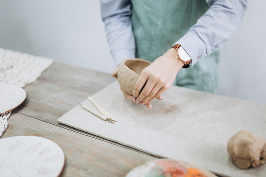 The potter's hands are shaped a cup from a clay. The process of creating pottery. The master ceramist works in his studio. Close-up, only hands. Crockery from clay own hands.