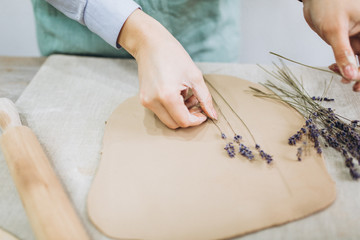 The potter's hands are shaped a cup from a clay. The process of creating pottery. The master ceramist works in his studio. Close-up, only hands. Crockery from clay own hands.
