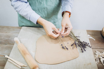 The potter's hands are shaped a cup from a clay. The process of creating pottery. The master ceramist works in his studio. Close-up, only hands. Crockery from clay own hands.