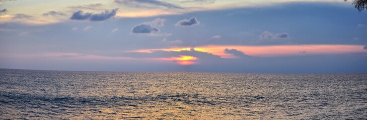 Phuket beach sunset, colorful cloudy twilight sky reflecting on the sand gazing at the Indian Ocean, Thailand, Asia.