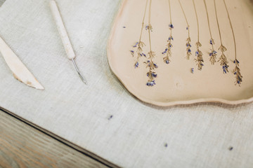 The process of creating pottery in studio.  Crockery from clay. Handmade dish with lavender flower