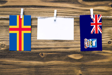 Hanging flags of Aland Islands and Falkland Islands attached to rope with clothes pins with copy...
