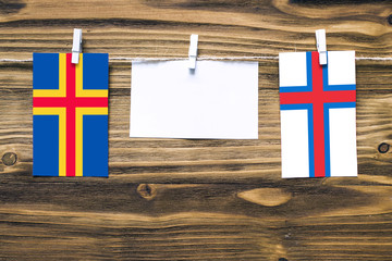 Hanging flags of Aland Islands and Faroe Islands attached to rope with clothes pins with copy space...