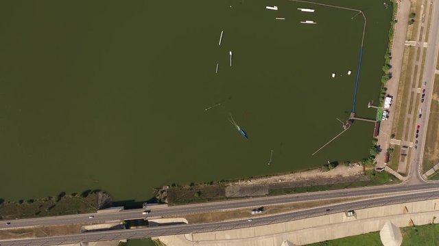 Flying over wakeboarding cable wake park HD aerial video. Wakeboarder doing jump tricks. Water extreme sport. Kaluga wakepark in Russia