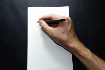The male left and right hand holds a pen over a white sheet of paper on a black background. Items per sheet, Sports and Fitnec