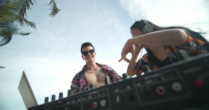 Happy asian male DJ playing music on a beach party.