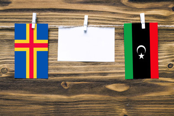 Hanging flags of Aland Islands and Libya attached to rope with clothes pins with copy space on...