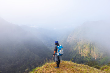 Obraz premium A backpack man standing on cliff and see over view in nature.Tourist enjoying fresh air. A man enjoying free happiness in beautiful Thailand landscape.